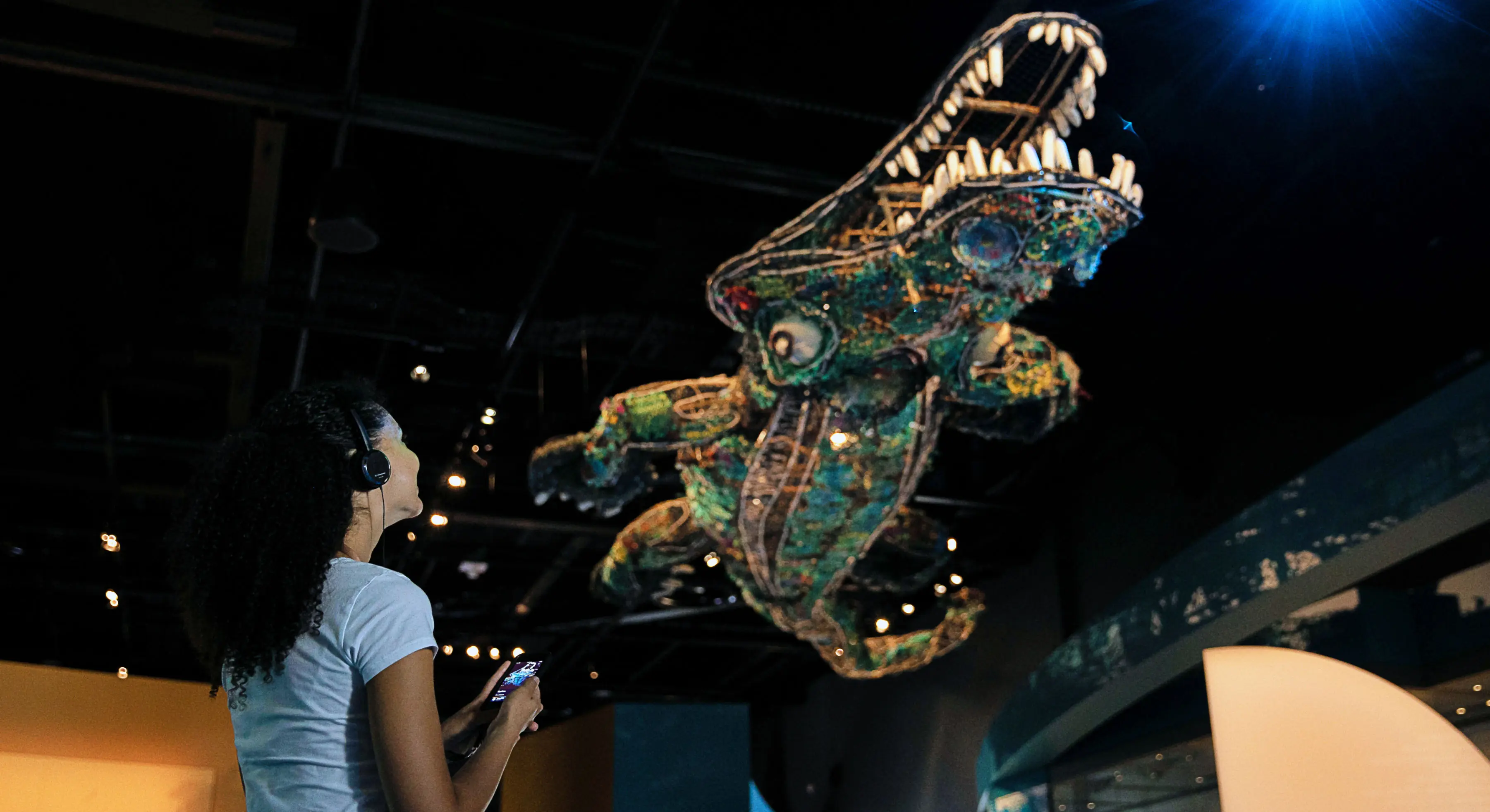 Visitor using the mobile audio guide near a ghostnet sculpture at WA Museum